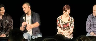 a man and woman sitting on a stage with microphones