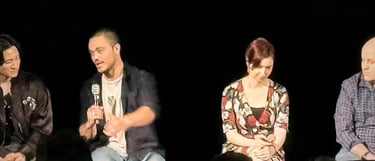 a man and woman sitting on a stage with microphones