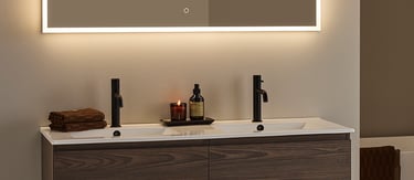 Modern floating double vanity with dark wood grain, matte black faucets, and a backlit LED bathroom mirror.