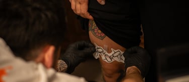 tatuointiartisti laittamassa siirtokuvaa asiakkaan jalkaan
