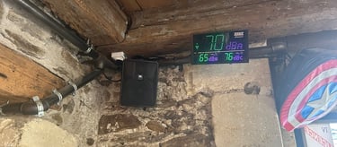 Sonmètre numérique et haut-parleur JBL monté sur un mur en pierre rustique avec des poutres en bois
