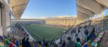 Estadio Bicentenario de La Florida, em Santiago do Chile, visto em dia claro com arquibancadas coloridas.