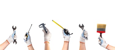 hands holding various handyman tools on a white background