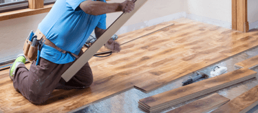 homem trabalhando colocando um piso de madeira laminado