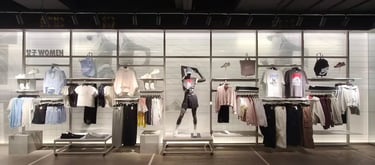 Nike women's sportswear display featuring mannequins, apparel on racks, and sneakers in a retail store.