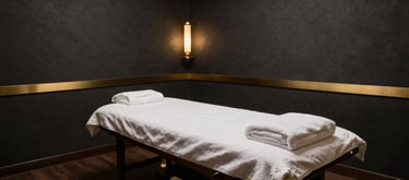 Interior view of a luxury Indian spa room with dark charcoal walls, gold accents, and a professionally prepared massage table.