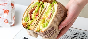 a person holding a sandwich sandwich in a paper bag