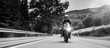 Picture of motorcycle head as it rides down a road with its headlight on