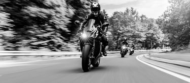 front view of three motorcycles travelling around a left hand bend one behind the other