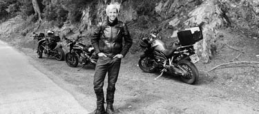 Dan next to three motorcycles parked up at the side of the road near a rocky area