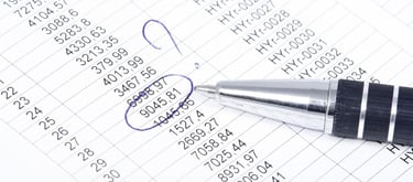 Un stylo posé sur feuille plein de chiffres