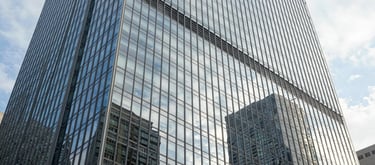 A stunning architectural shot of a glass and steel skyscraper in a major North American city, reflecting the sky and representing stability and innovation.