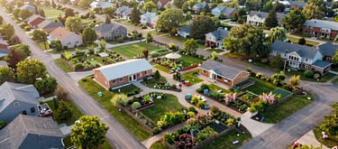 A serene, clean aerial view of a vibrant North American neighborhood where community gardens and well-maintained educational centers are prominent. The lighting is early morning, soft and inspiring.