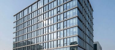 A sleek, modern architectural photograph of the Zoevita Pharmaceuticals headquarters in India, featuring glass windows reflecting a clear blue sky and professional landscaping.