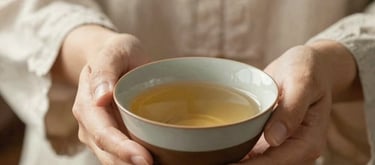 A woman's hands gently holding a ceramic bowl of tea, soft sunlight, focus on the texture of the linen clothes and the earthy tones of the pottery, calm and nurturing mood.