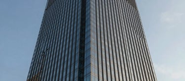 The exterior of a modern glass skyscraper in São Paulo during golden hour, reflecting the blue sky, emphasizing innovation and leadership.