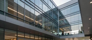 Architectural shot of a modern office lobby in Brasilia. Clean lines, minimalist aesthetic with steel blue and grey accents. The space is filled with soft, diffused morning light, emphasizing transparency and professional excellence.