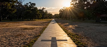 A wide-angle landscape shot of a peaceful Georgia park at sunset, with golden light illuminating a paved walking path that symbolizes the journey of faith. The composition is calm and professional, featuring sand and deep blue tones.