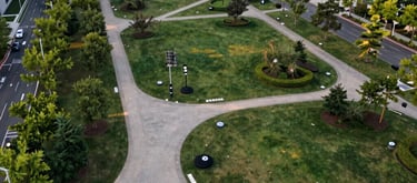 A high-altitude aerial view of a modern city park integrated with hidden environmental sensors. The composition is clean and organized, featuring paths and greenery under soft afternoon light in North America.