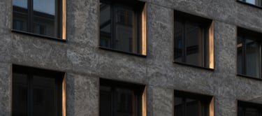 Minimalist architectural facade of a modern residential building in Zurich, dark concrete, elegant bronze window frames, dramatic chiaroscuro lighting, landscape aspect