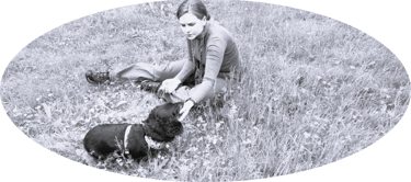 Dog walker in field with dacshund - black and white