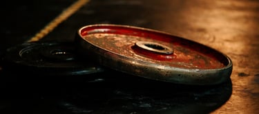 Worn red and black weight plates resting on a dark gym floor with dramatic lighting.