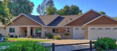 Ranch style home remodeled with tan lap siding, white trim, and brown board and batten gable.