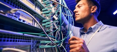 IT technician managing ethernet cables and network servers in a modern data center.