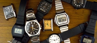 a bunch of watches on a table with a clock