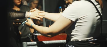 A staff member secures a festival wristband on a guest's arm at a concert event entrance.
