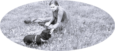 Dog walker in field with dacshund - black and white