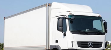 Trucks and equipment transporting materials on a rugged terrain.