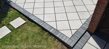 Basic grey patio with black charcoal edging blocks slabs laid in diamond format