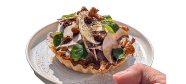 Une personne tient une assiette avec une tartelette généreuse