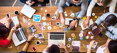 a group of people sitting around a table with laptops