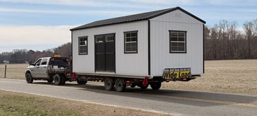 Shed being delivered on the back of a truck and trailer