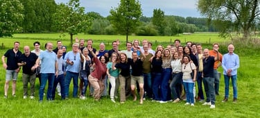 Groepsfoto van enthousiaste deelnemers tijdens Talenttrainer evenement in groene landelijke omgeving