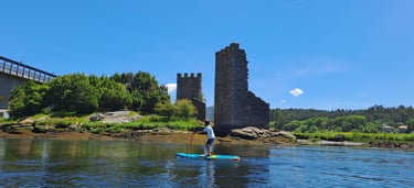 Chico remando con un paddle surf frente a las torres del oeste de Catoira