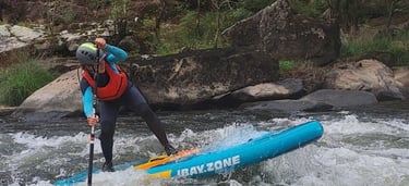 Una chica remando sobre un rápido del río ulla