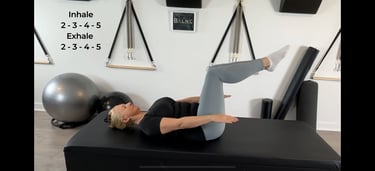a woman performing Pilates Hundreds exercise
