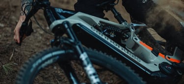 Tattooed rider cornering a Cannondale electric mountain bike on a dirt trail.