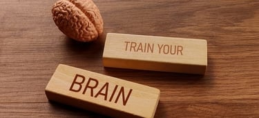 A human brain model next to wooden blocks reading Train Your Brain for cognitive health.