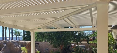 Hip ridge beam and mitered rafters on aluminum pergola in front of planter area.