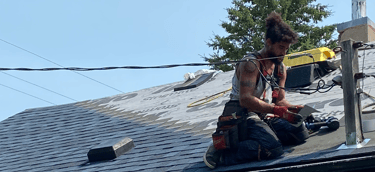 Professional roofing contractor installing new asphalt shingles on a residential house roof.
