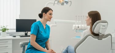 Una dentista hablando amistosamente con un paciente sentado en el sillón dental