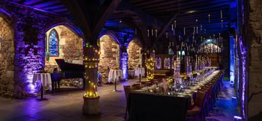 Indoor event setup with elegant lighting and long dining tables, themed Harry Potter