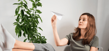 femme avec avion en papier en train de procrastiner