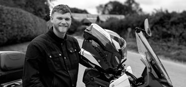 Paul standling alongside his Honda Transalp motorcycle at the roadside of a country lane