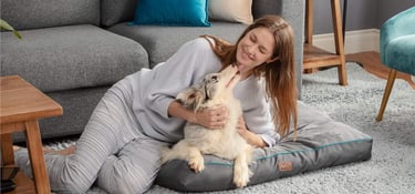 a woman sitting on a dog bed with her dog