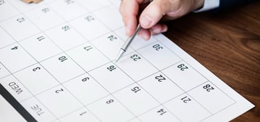 Close de profissional agendando compromisso em calendário de papel, simbolizando organização e planejamento